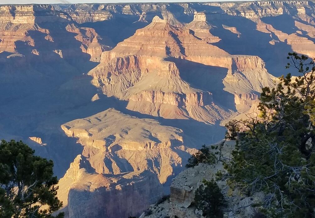 This color photograph shows a view of the red and cream-colored, flat-lying sedimentary rocks in the Grand Canyon and the blue s