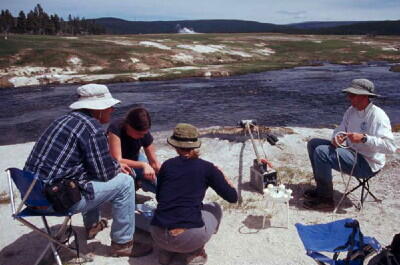 USGS scientists collecting a water sample from a spring in Yellowstone National Park.