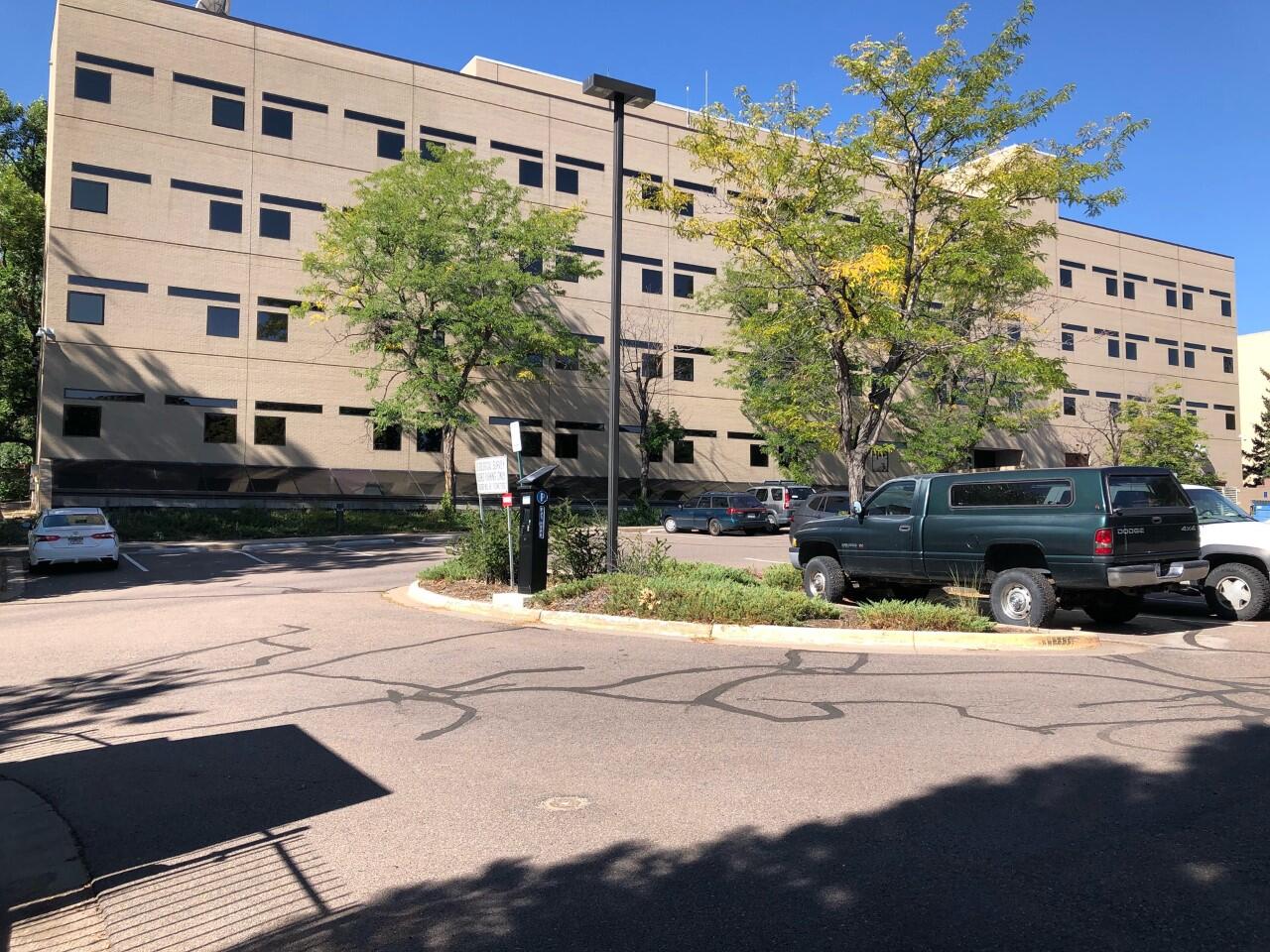 parking lot with a couple of trees in front of a 5-story building