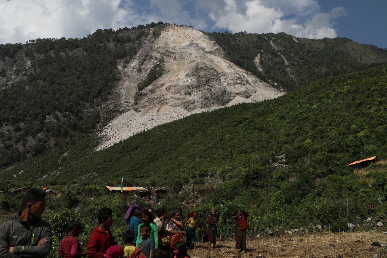 Villagers in Kerauja, Nepal standing below a large rock slide