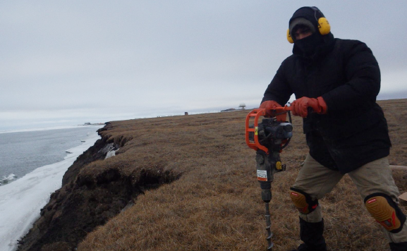 U.S. Geological Survey scientist drilling into the Alaskan tundra.