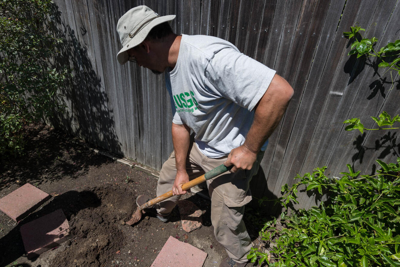 Mark Goldman prepares a hole in a volunteer’s yard to place a seismometer
