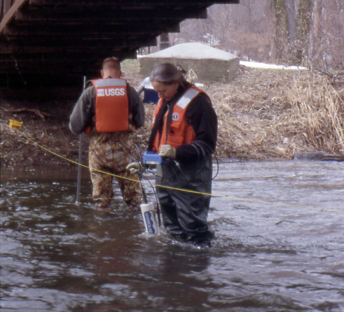 Field technicians measuring field parameters with a multiparameter meter in a stream during a reconnaissance study