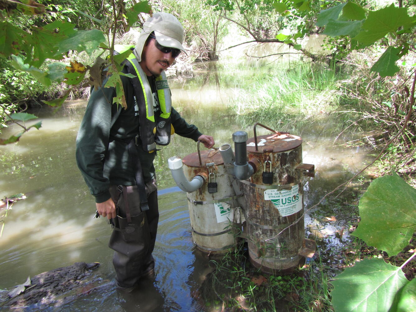 Hydrologic technician removing bottles from passive samplers after a storm.