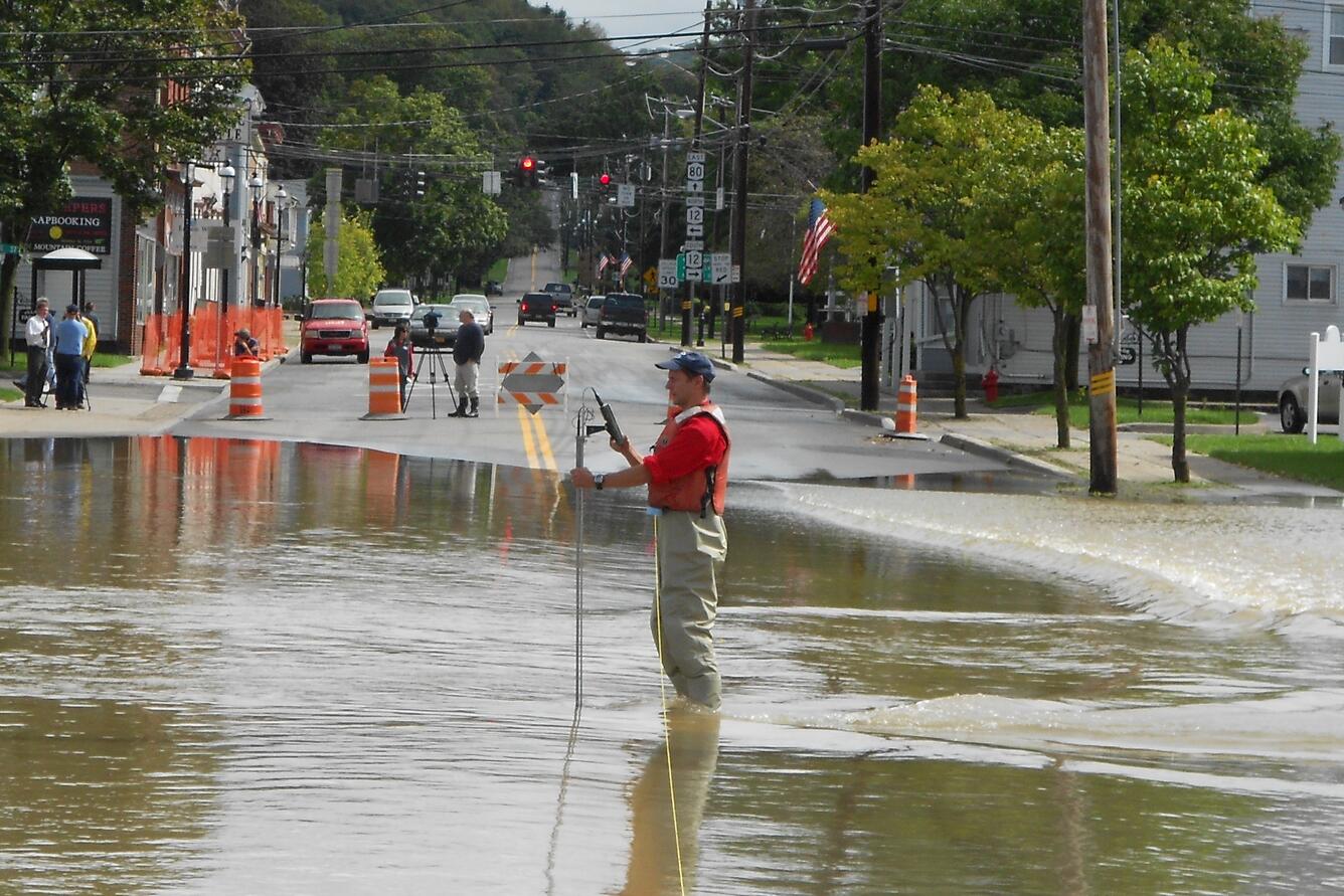 man making flowtracker measurement on flooded street