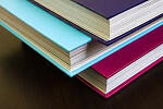 Blue, Purple and pink book sitting on a table