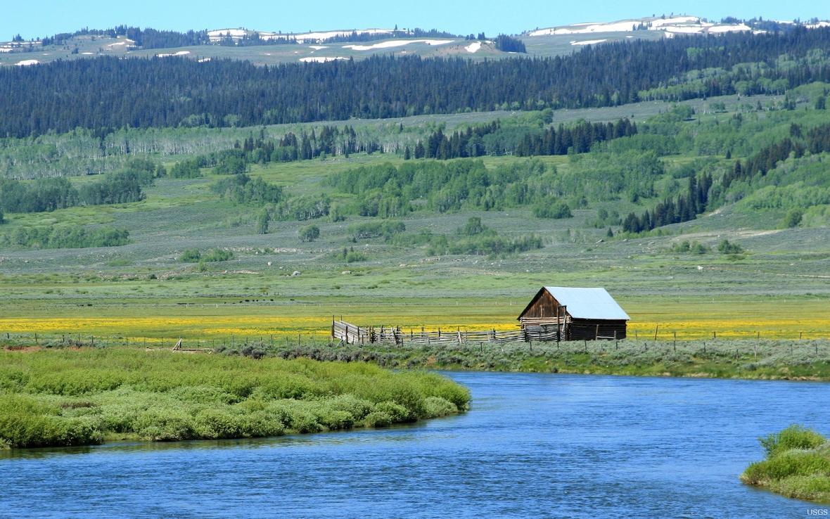 View of the Green River flowing though a valley with a ranch house on the shore
