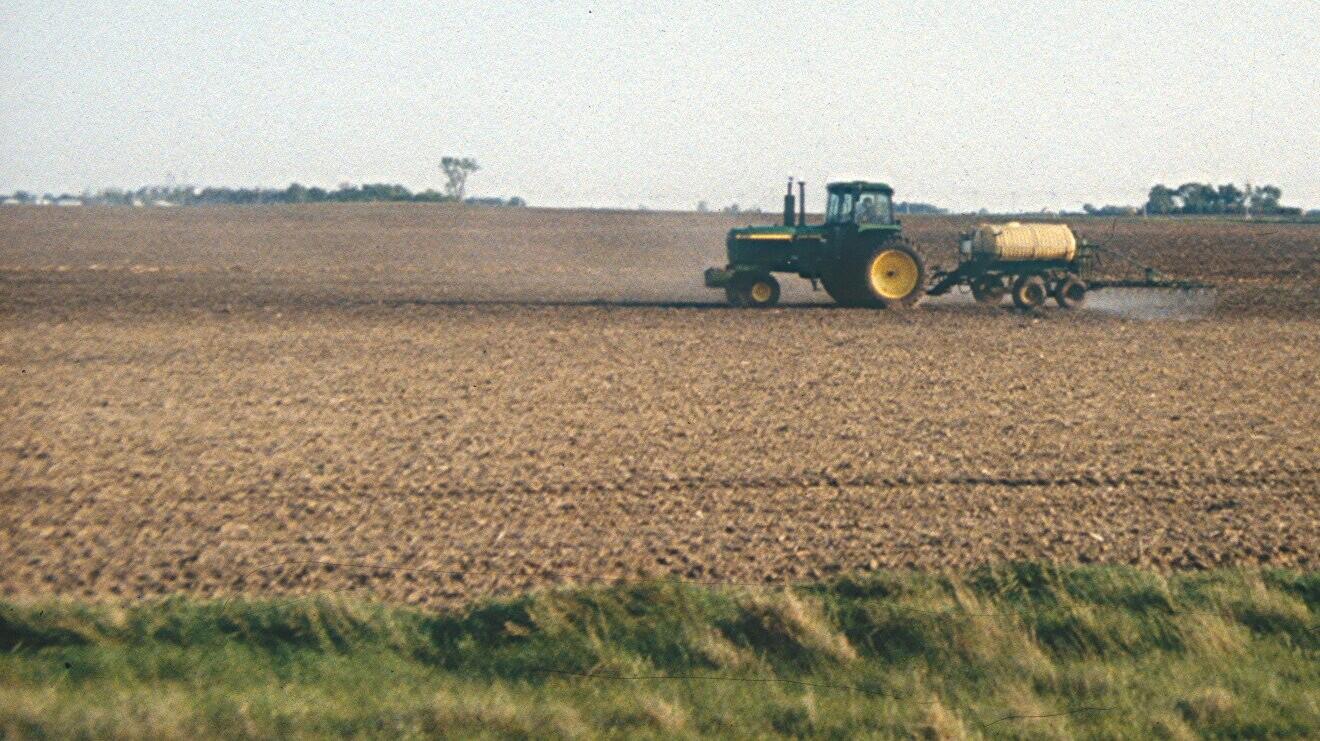 Farm field with tractor applying herbicides