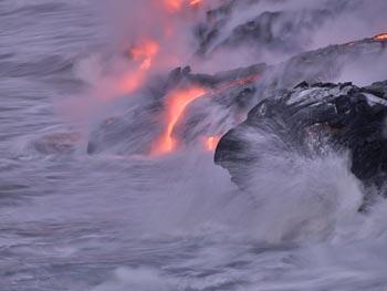 Lava in Banana flow plunges into ocean with surf crashing against rocks.