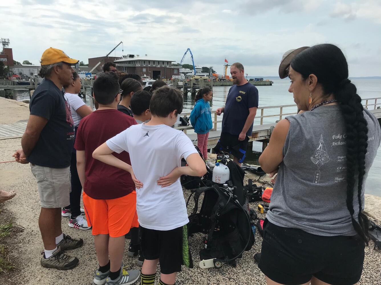 Native American youth gathered on a dock looking at diving equipment USGS scientists use to study coastal changes