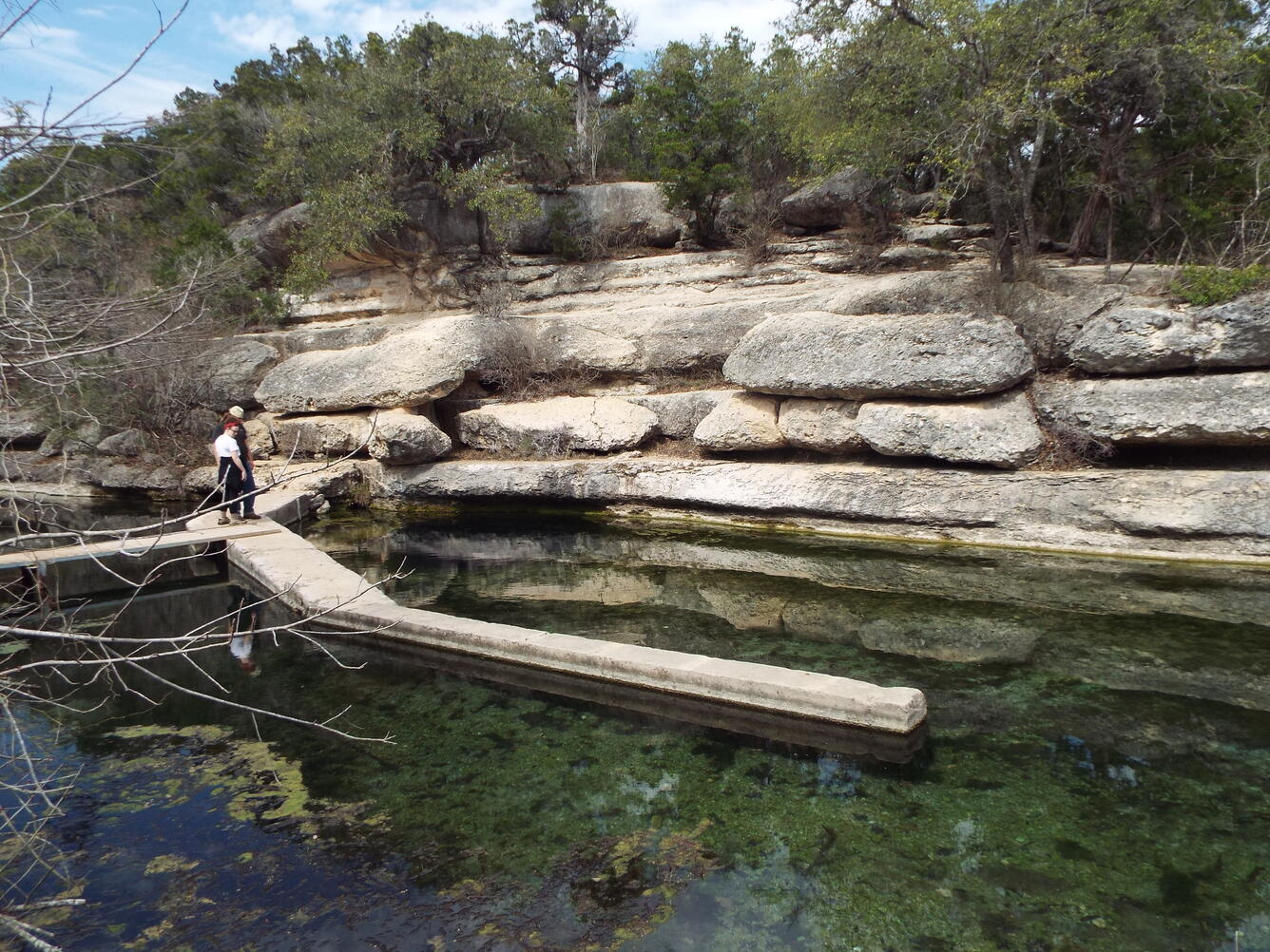 Two scientists stand on a path over Jacob's Well, near Wimberley, Texas.