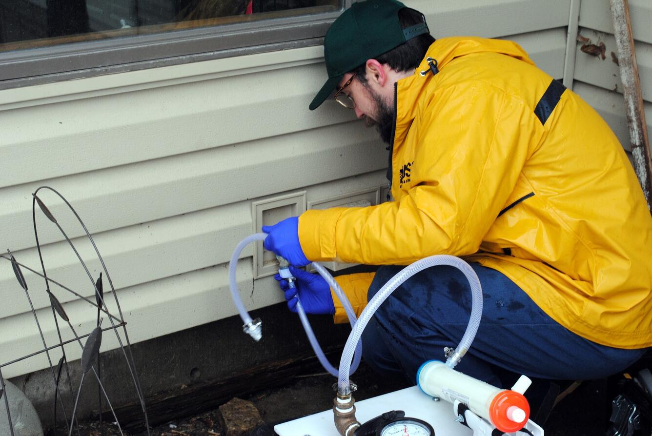 risk assessment research studies Scientist collecting homeowner water sample