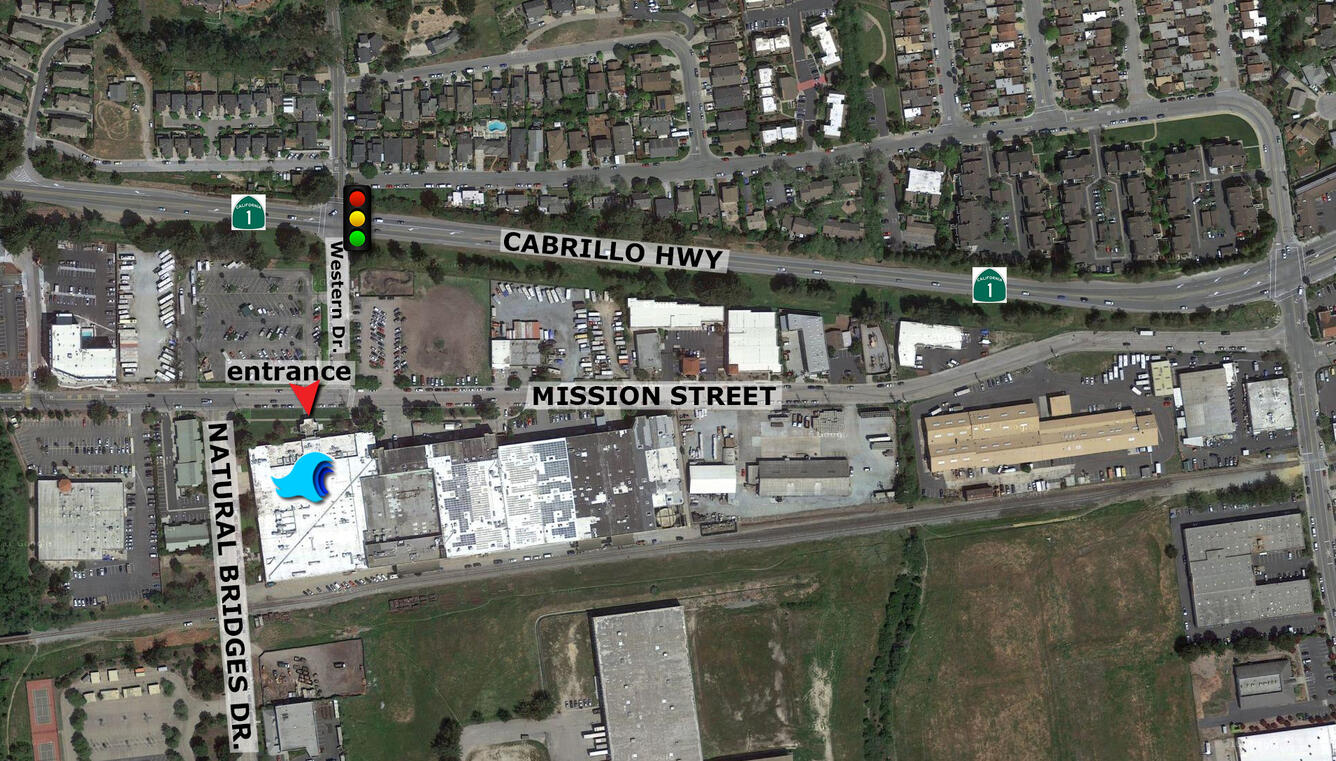 View from the sky of streets, buildings, and houses, with street labels and an entrance to a building marked with an arrow.