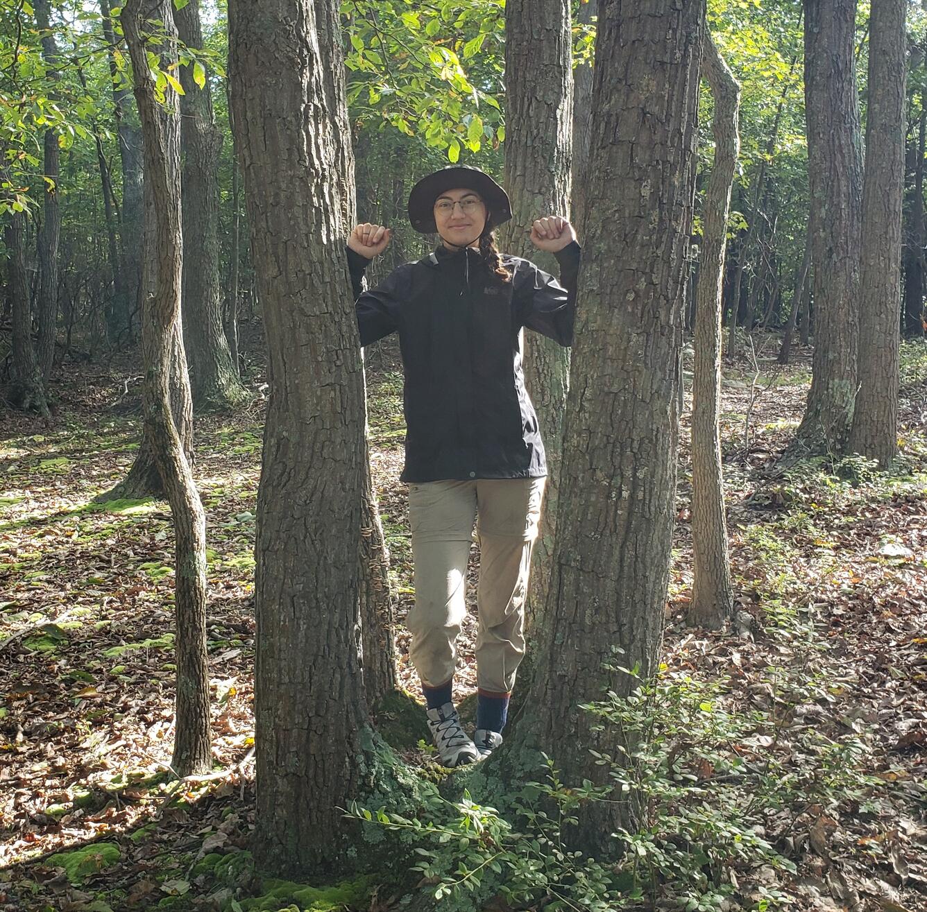 photo of HFA, Leah Staub, in between two Quercus Montana trees.