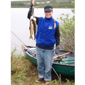 Portrait of Mandy Stone standing by a boat on a lake holding a stringer of fish