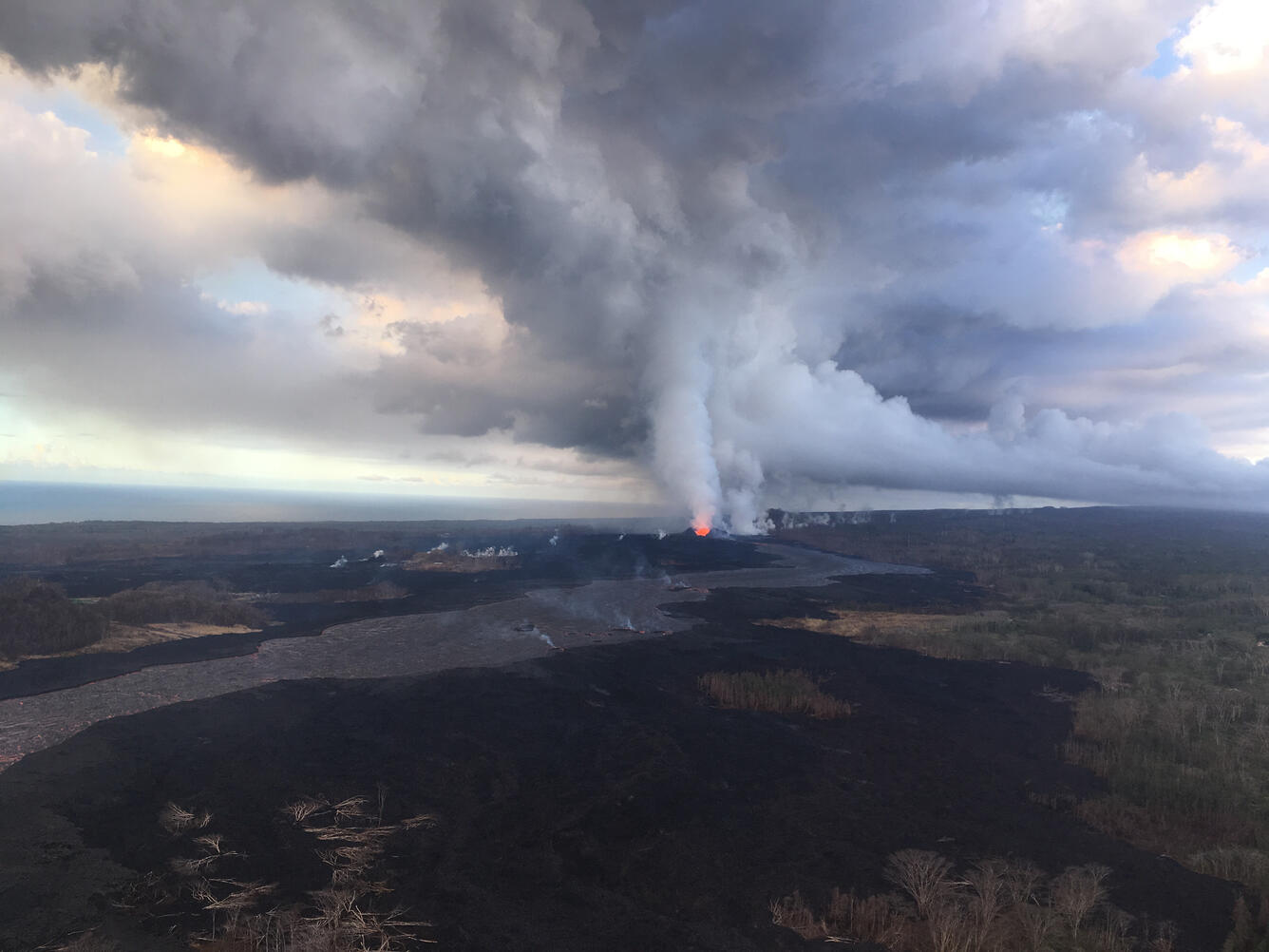 Fissure with lava channels and plumes rising into the sky