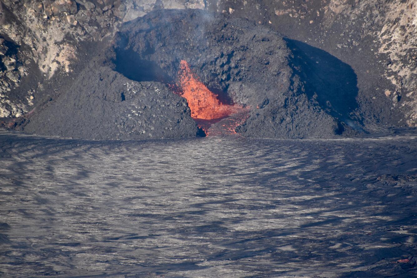 Color photograph looking into the west vent spatter cone with a small lava fountain in the center