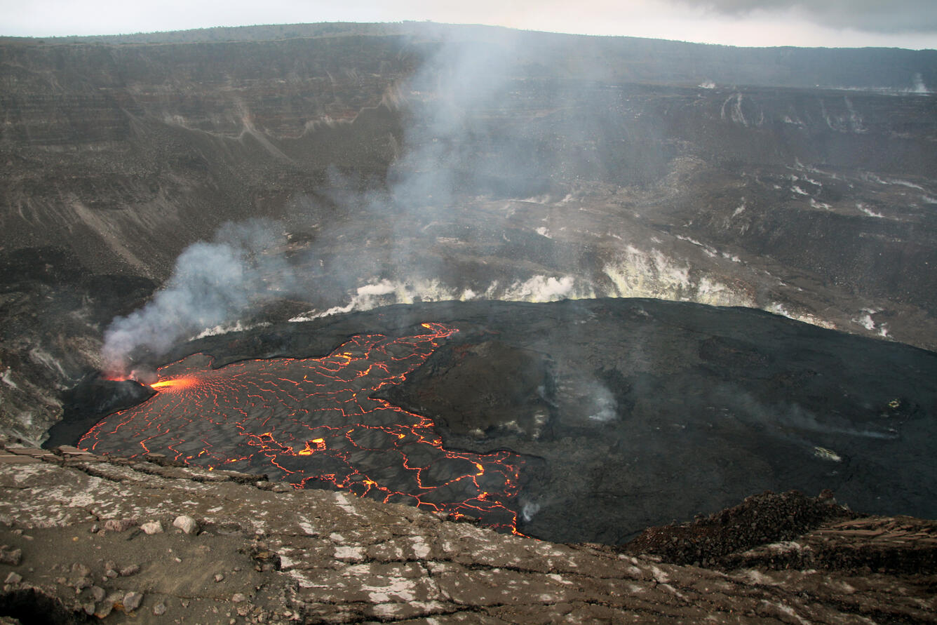 Wide view of a lava lake, with the active lava lake and vent on the left and the dark solidified surface on the right