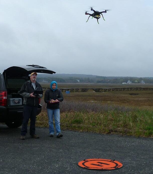 Pilots prepare to land a quadcopter drone after a beach mapping flight