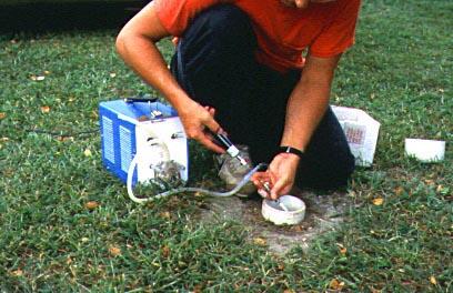 Scientist collecting gas samples from ground site 