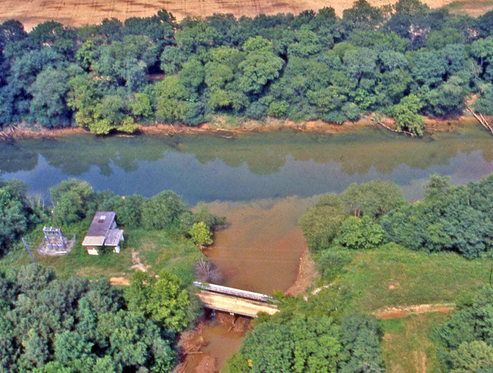 Image shows the brown tributary entering the blue Chattahoochee River from below