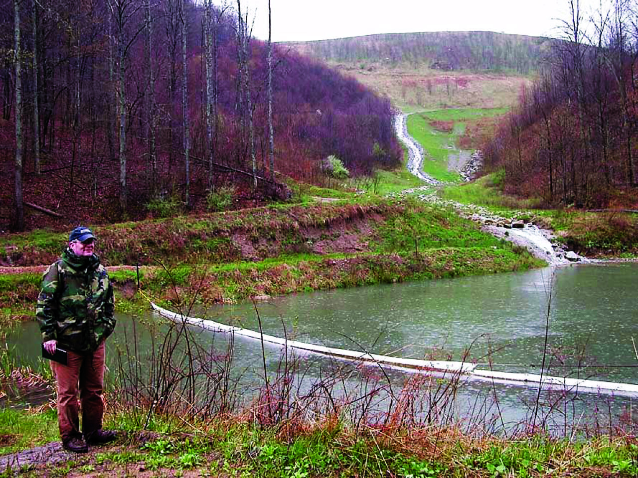 A USGS scientist standing next to a valley fill pond in West Virginia.