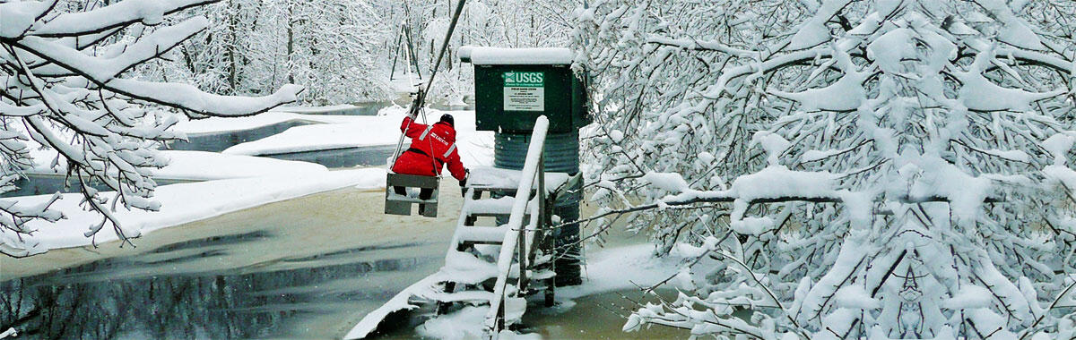 A hydrologist using a cableway to access a river gage monitoring site