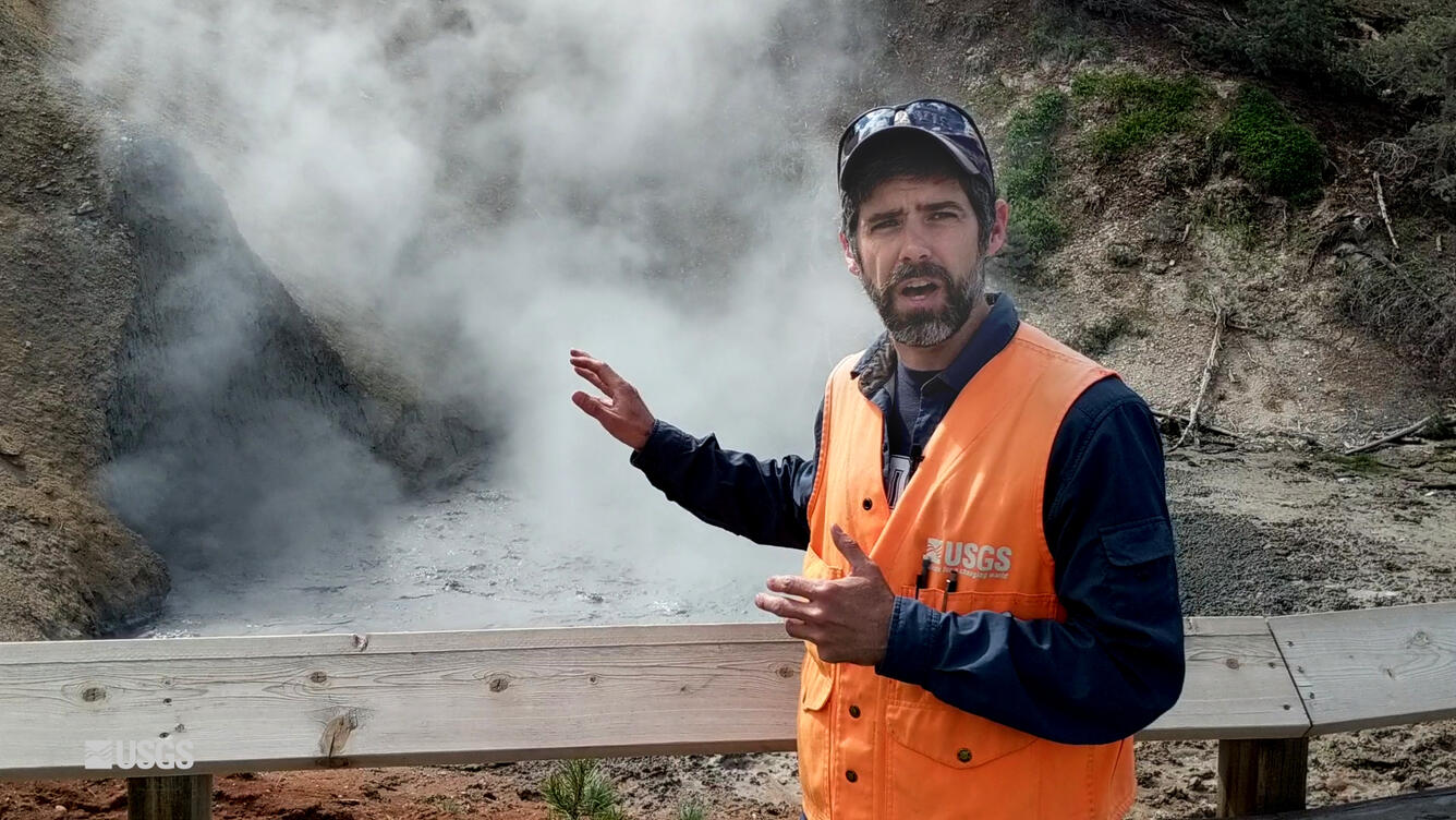 Man standing in front of a geyser with orange vest on