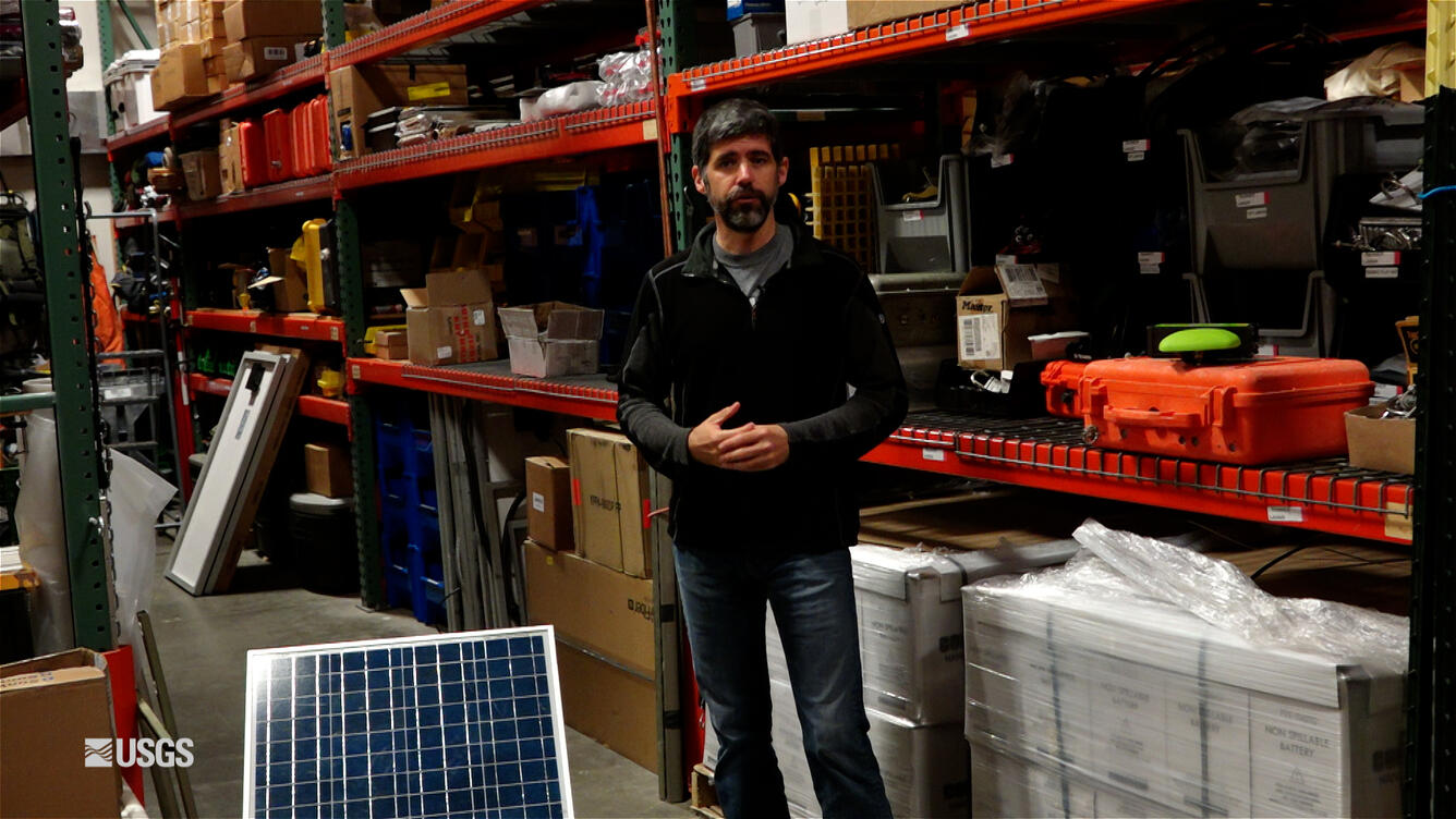 Person standing in front of shelves with scientific equipment.