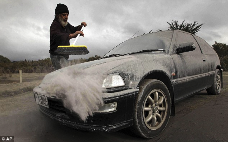 Man brushing ash of car following the 2012 Tongariro eruption, New ...