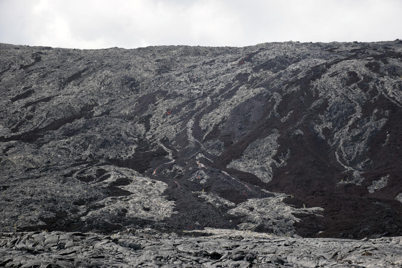 ‘A‘ā flowing down Pulama pali in multiple small channels, with oran...