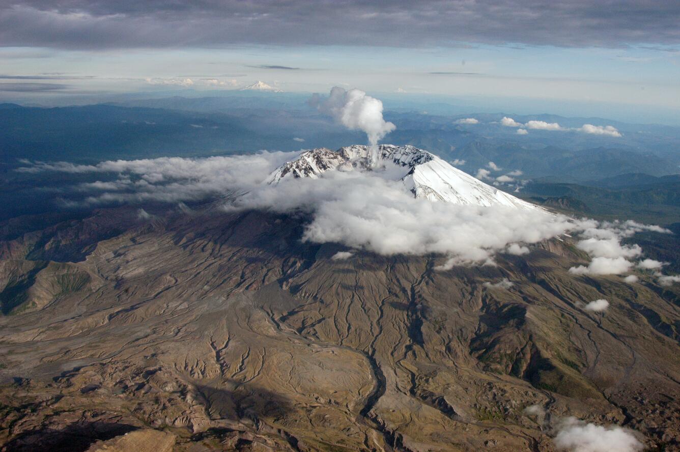 South-facing aerial view of Mount St. Helens with Mount Hood (left)...