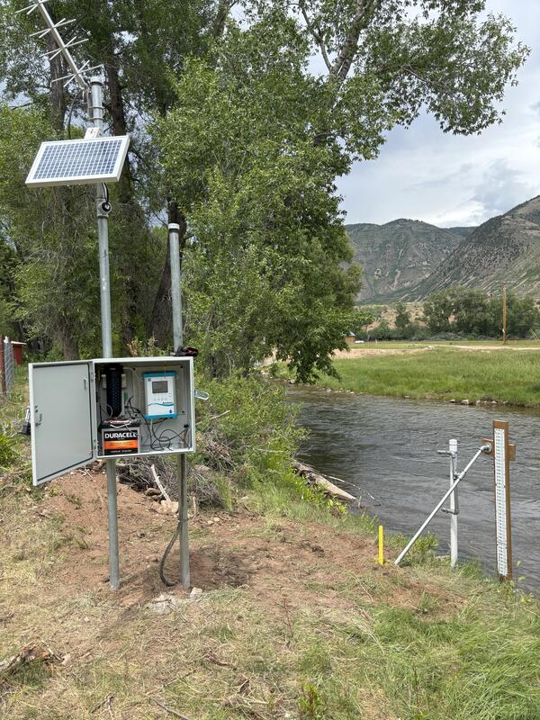 Gaging station and staff plate on grassy streambank.