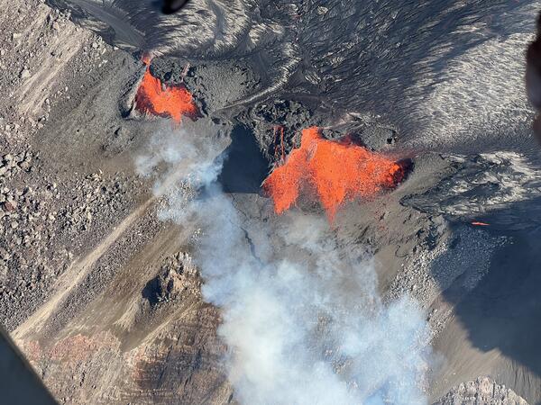 orange lava fountains erupting from black lava within crater