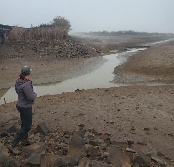 narrow channel winding through brown sediments on a cloudy day