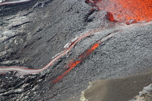 Color photograph of lava flows from erupting volcanic vent
