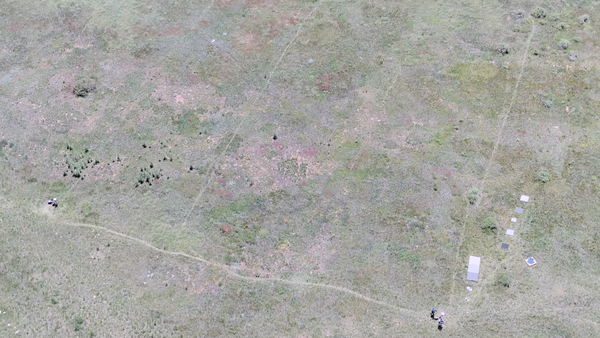 Aerial photo looking down at a field with drone operator and reference objects used for calibration of payload instruments