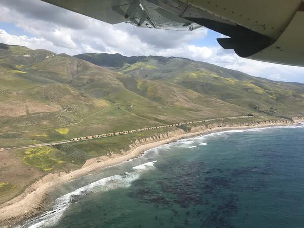 California coast showing a train and spring flowers, viewed from a plane over the ocean