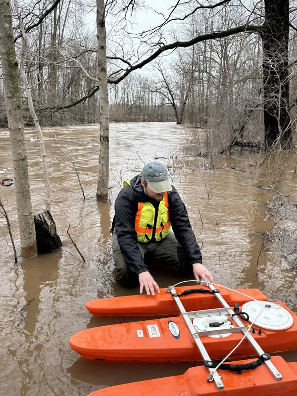 hydrologic technician prepares to measure streamflow on flooded creek with ADCP