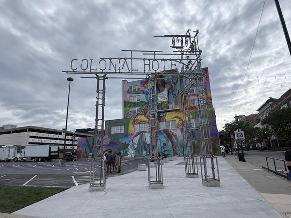 Metal framework resembling an old hotel sign with “Colonial Hotel” across the top