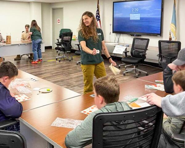 USGS employee smiles while interacting with students sitting at an L-shaped table