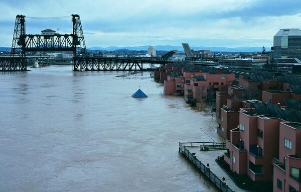 dark brown water is higher than the riverbank and completely covering some buildings.