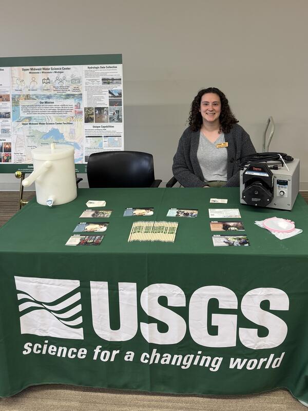 Hydrologist sits behind a USGS table at a career fair