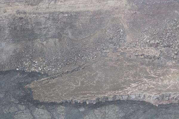 Color photograph showing cold lava flows that are getting close to a damaged road