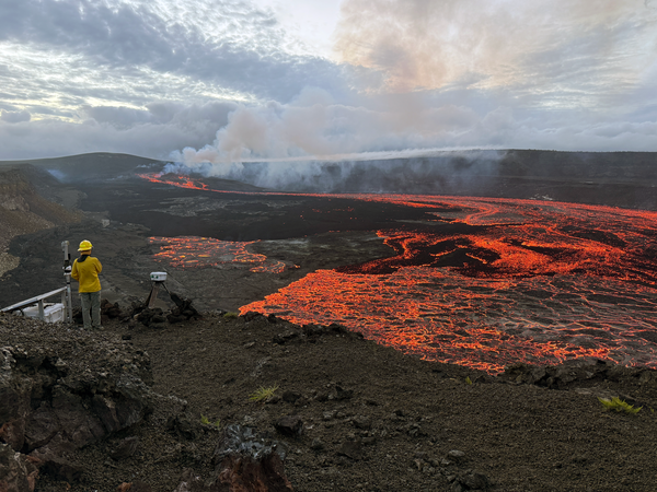 Red, incandescent lava flows cover a large portion of a crater floor
