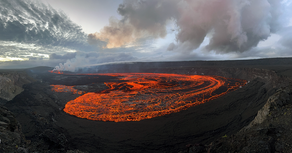 An incandescent red lava flow covers a large area of a crater floor