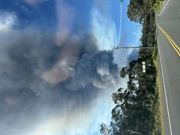 Color photograph of a volcanic plume rising above a highway