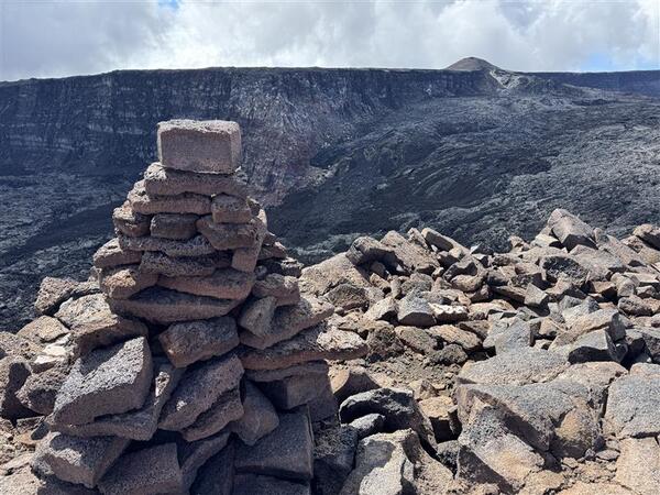 Color photograph of trail cairn near volcanic caldera
