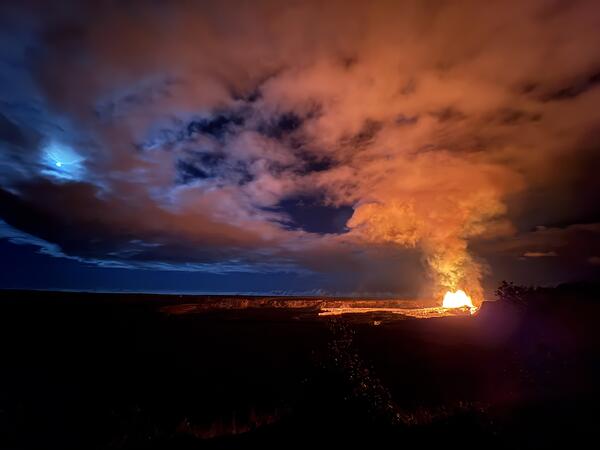 Color photograph of volcanic eruption and full moon