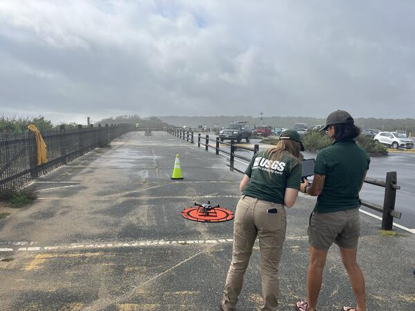 Two people in parking lot standing in front of drone